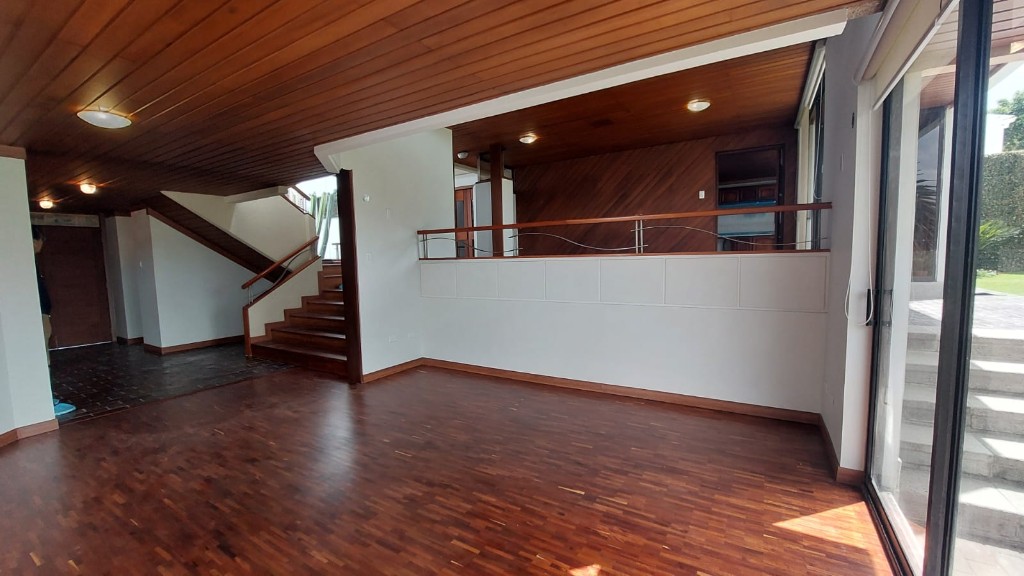Sala amplia con piso de madera y doble altura